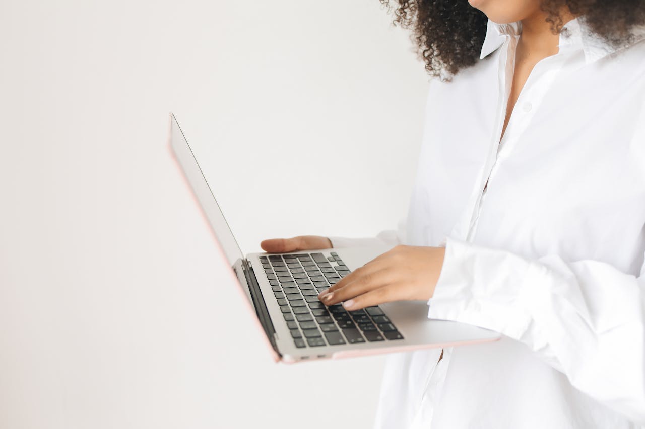 A close-up shot of a woman working on a laptop with focus on her hands.